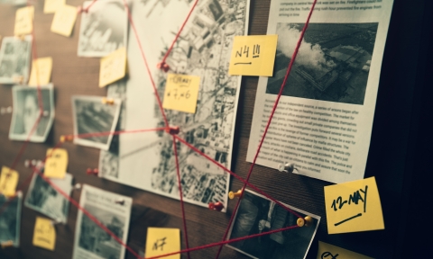 Detective board with photos of suspected criminals, crime scenes and evidence with red threads
