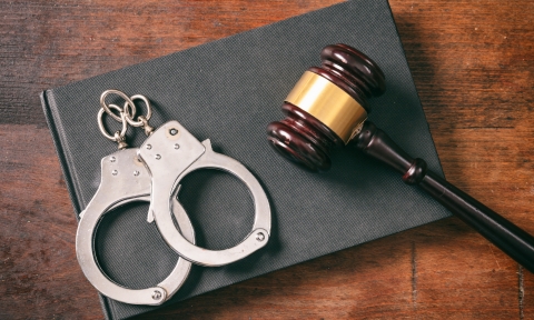 Handcuffs, gavel on book on a wooden background.