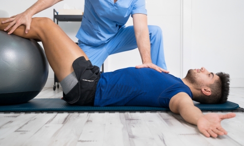 Physiotherapist helps handsome young patient with pilates exercises. High quality photo