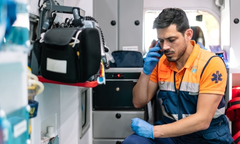 young and handsome paramedic talking on the phone inside an ambulance ready to attend to an emergency