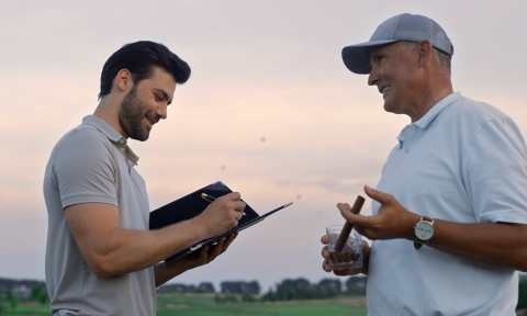 Two men talking golf course outside. Golfers analyze game result at sunset field
