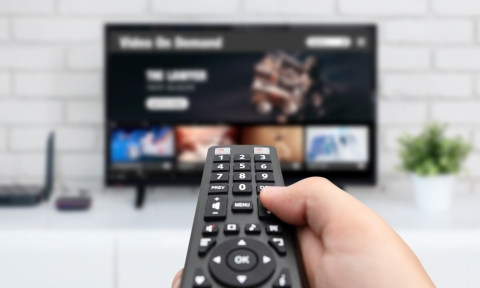 Man watching TV, remote control in hand